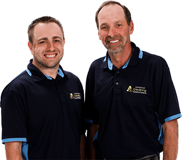 Two smiling men in matching blue and black company polo shirts standing side by side against a white background